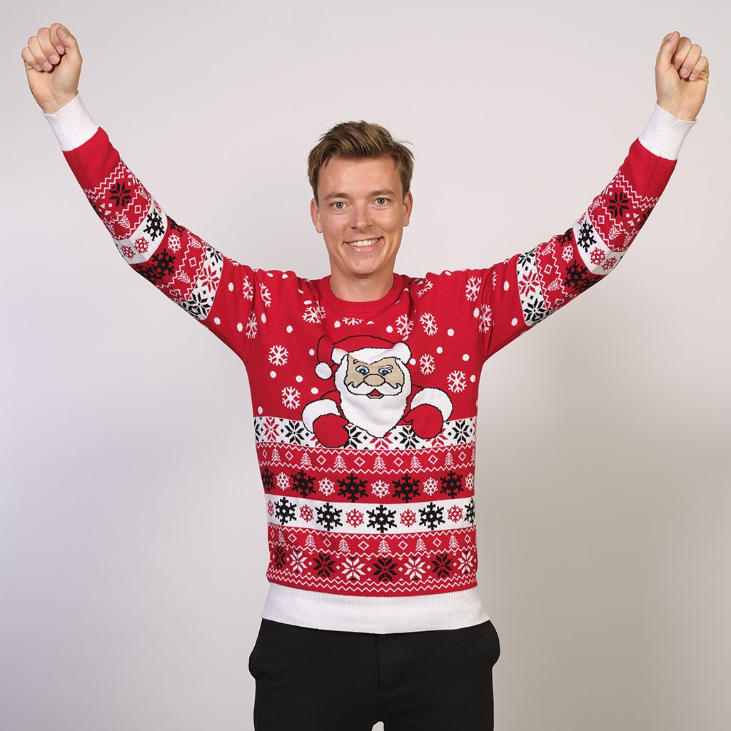 Un homme portant un pull de Noël rouge avec le Père Noël et des flocons de neige.